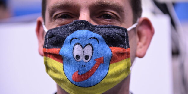 Ein Mann trägt eine Maske mit Deutschlandfarben und AFD Logo