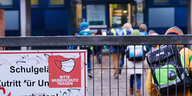 Ein Gittertor und Schulkinder dahinter: „Bitte Mundschutz tragen“ steht am Eingang zu einer Grundschule in Friedrichshain