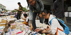 Zwei indonesische Studenten schauen sich Bücher auf einem Flohmarkt an.