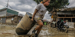 Eine Frau rettet ihre Habseligkeiten nach einem Taifun auf den Philippinen