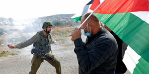 Konfrontation zwischen einem Mann mit palästinensischer Flagge und einem israelischen Soldaten