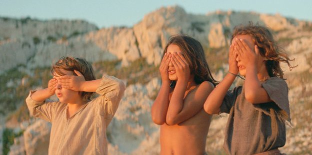Drei Kinder vor einem Gebirge. Sie halten sich die Hände vor die Augen.
