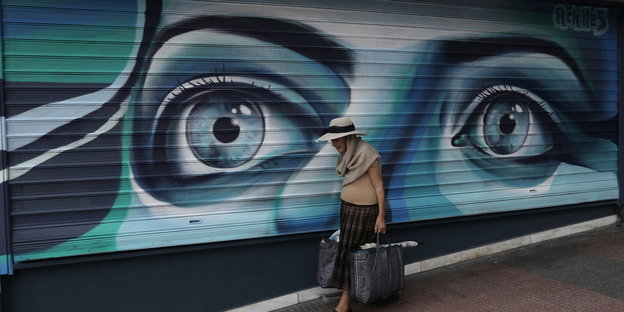 Einkäuferin vor großem Graffitto in Athen