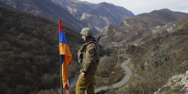Ein armenischer Soldat steht neben einer Flagge in der bergigen Region von Bergkarabach