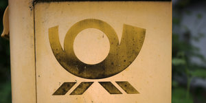 Gelber Briefkasten mit Logo der Post.