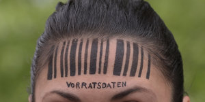 Eine Frau hat einen Barcode auf die Stirn gezeichnet