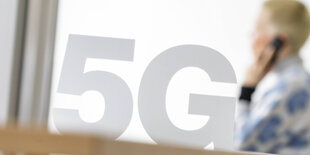 Eine Frau telefoniert mit einem Handy hinter einem 5G Symbol