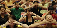 Menschen halten sich in Manila beim Welt-Yoga-Tag die Augen zu