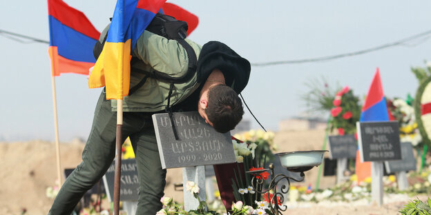 Armenien, Yerevan: Ein Mann küsst den Grabstein eines gefallenen Soldaten in der Region Berg-Karabach