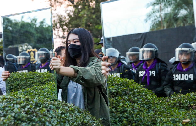 Demonstranten halten Thailändischen Polizisten einen Spiegel vors Gesicht