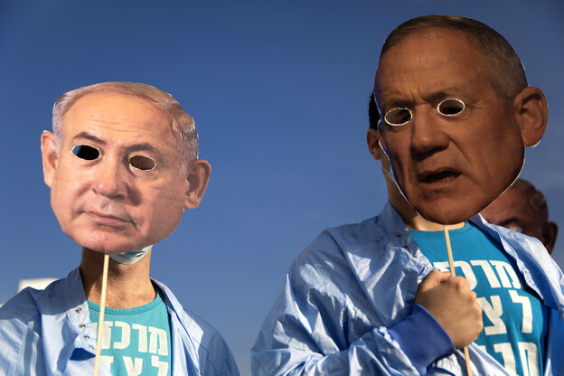 Demonstranten halten eine Benjamin Netanyahu-Maske vors Gesicht - unter ihm ein angeschnittenes Plakat einer Krankenschwester