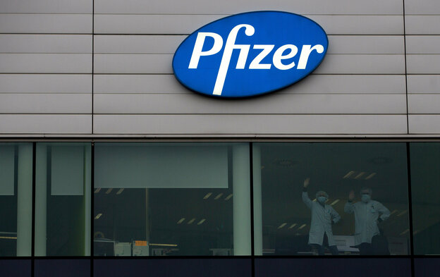 Mitarbeiter von Pfizer winken aus dem Fenster aus der Niederlassung des Pharmaunternehmens in Puurs, Belgien