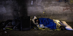 Zwei Obdachlose Männer schlafen, einer der Männer hat keine Decke