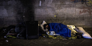 Zwei Obdachlose Männer schlafen, einer der Männer hat keine Decke