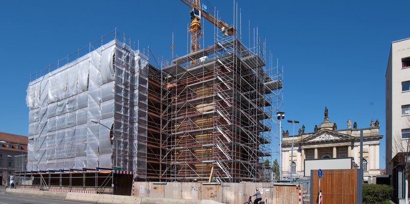 Ein kran steht hinter einem Gerüst auf einer Baustelle