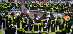 Feuerwehrleute halten sich gegenseitig in Augsburg, nachdem einer ihrer Kollegen ums Leben gekommen ist