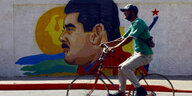 Ein Radfahrer fährt an einem Graffiti vorbei, das Nicolás Maduro , den Präsidenten von Venezuela zeigt