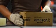 Eine Mitarbeiterin am Amazon Standort Graben bei Aachen verpackt ein Paket mit Schutzhandschuhen