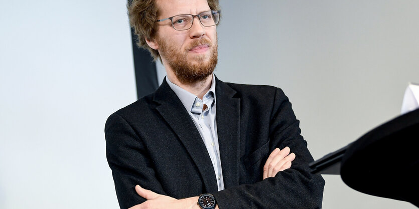 Das Bild zeigt den Grünen-Baustadtrat von Friedrichshain-Kreuzberg, Florian Schmidt, im dunklen Jacket mit vor der Brust gefalteten Armen.