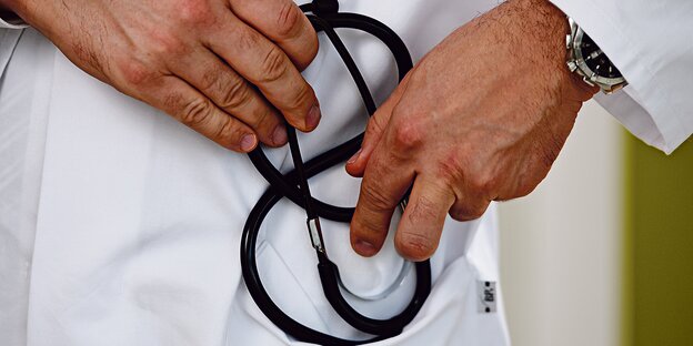 Ein Mann in einem weißen Kittel hält ein Stetoskop