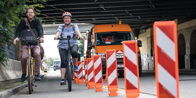 Auf dem Rad mit Helm: Florian Schmidt, Bezirksstadtrat, und Monika Herrmann, Bezirksbürgermeisterin des Bezirks Friedrichshain-Kreuzberg, begutachten die Montage der Leitboys auf dem Radfastreifen in der Tamara-Danz-Straße