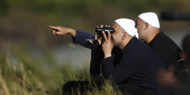 Zwei Geistliche der Drusen schauen mit Ferngläsern über die Golanhöhen