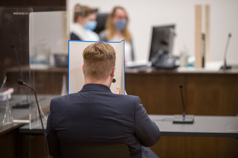 Mann sitzt im dunklen Jacket vor Tisch von hinten