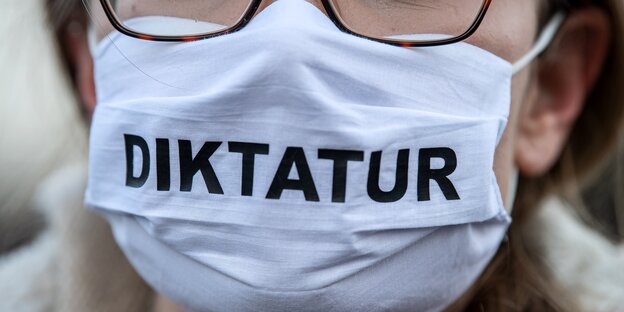 Demonstrantin mit Aufschrift "Diktatur" auf Gesichtsmaske