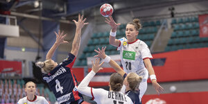 Die Deutsche Emily Bolk springt hoch und wirft den Ball in Richtung ihrer Teamkollegin Julia Behnke, während Norwegerinnen versuchen, zu blocken