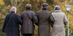 Vier ältere Menschen spazieren in einem Park