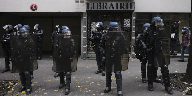 Französische Polizisten mit Helmen stehen vor einer Bücherei