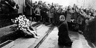 Willy Brandt kniet umringt von Fotografen vor dem Denkmal