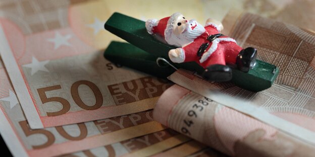 Eine Klammer mit Weihnachtsmann-Figur hält 50-Euro-Scheine zusammen