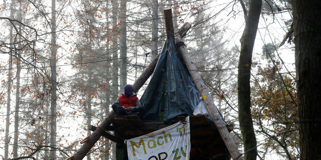 Ein Aktivist sitzt auf einer Tripod-Holzkonstruktion im Dannenröder Forst