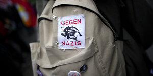 Symbolbild eines beigen Rucksacks, auf dem ein Aufnäher "Gegen Nazis" befestigt ist