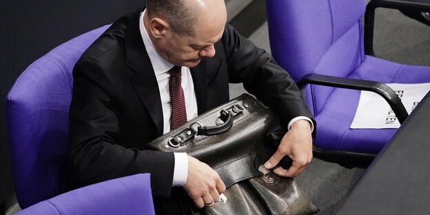 Finanzminister Scholz schließt seine Tasche im Budestag
