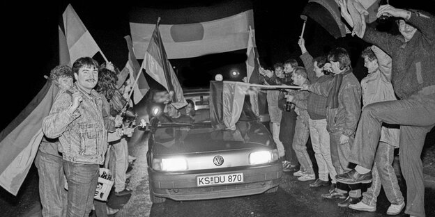 Schwarz-weiß Foto: Ein Auto fährt durch einen Spalier von Menschen mit Deutschlandflaggen