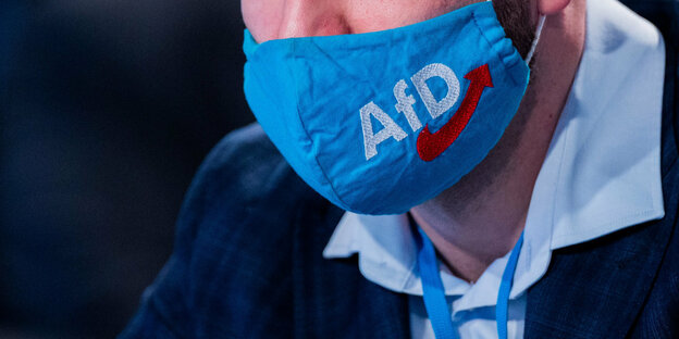 Eine Kinnpartie mit Maske mit einem AfD-Logo darauf