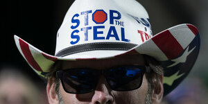 Ein Mann mit Sonnenbrille trägt einen Cowboyhut mit der Aufschrift "Stop the Steal" (Stoppt den Stimmenklau)