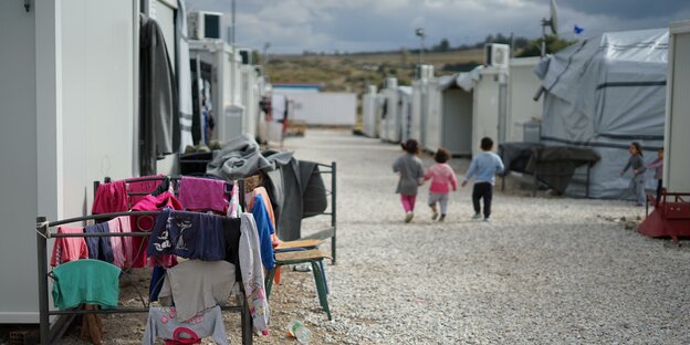 Container und Wäsche und drei Kinder in einem Camp für syrische Geflüchtete