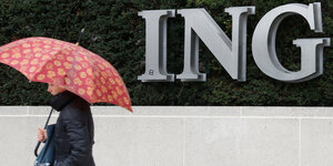 Ein Mann mit Regenschirm läft vor dem ING Logo entlang