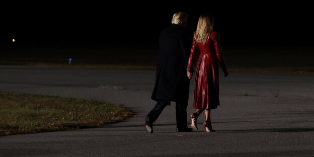 Donald Trump in schwarz und Melanie in rot gekleidet von hinten zu sehen