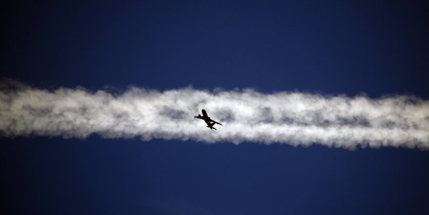 Ein Flugzeug fliegt unter dem Kondensstreifen eines anderen Flugzeugs hindurch