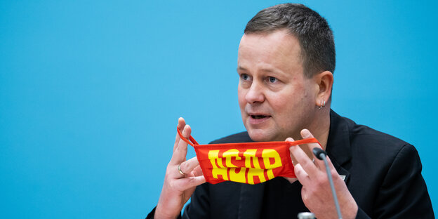 Klaus Lederer (Die Linke), Berliner Kultursenator, hält bei der Pressekonferenz nach der Sitzung des Berliner Senats eine Maske mit der Aufschrift "ASAP" in den Händen. Die Abkürzung "ASAP" steht für "as soon as possibel"
