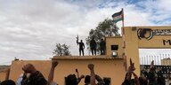 Mitglieder der Unabhängigkeitsbewegung Polisario stehen auf einem Gebäude und strecken Waffen in die Luft - vor ihnen jubelnde Menschen