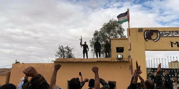 Mitglieder der Unabhängigkeitsbewegung Polisario stehen auf einem Gebäude und strecken Waffen in die Luft - vor ihnen jubelnde Menschen