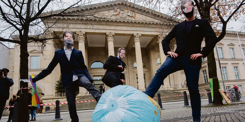 Klimaschützer mit Politikermaske spielel Fußball mit der Erde