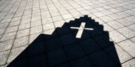 Schatten eines Gebäudes mit Kreuz auf dem Asphalt