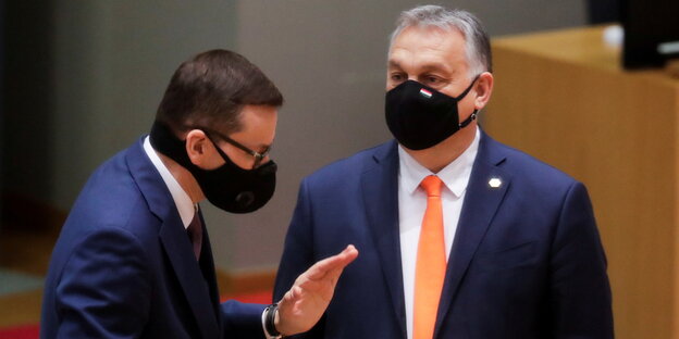 Viktor Orban und Mateusz Morawiecki diskutieren. Sie tragen beide Masken.