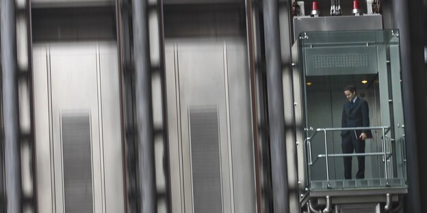 ein Banker fährt im gläsernen Aufzug am Llloyd's Building London